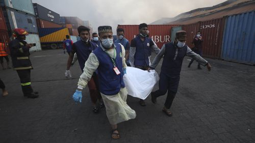 Le persone trasportano il corpo di una vittima dopo che è scoppiato un incendio nel deposito di container BM Inland.  (Foto AP)
