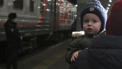 A woman carries a child as they are evacuated from the Donetsk region, the territory controlled by pro-Russia separatist government in eastern Ukraine, as they leave a train to be taken to temporary accommodations, at the railway station in Nizhny Novgorod, Russia.