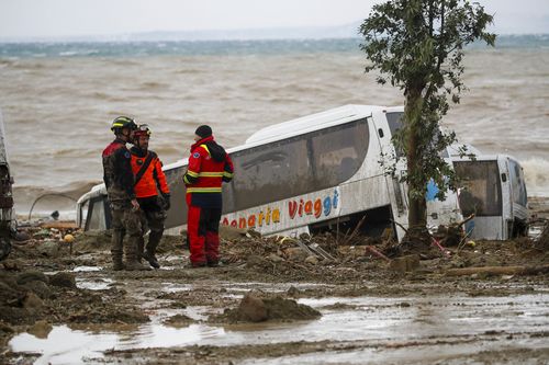 Rescuers stand next to a bus carried away after heavy rainfall triggered landslides on the southern Italian island of Ischia.