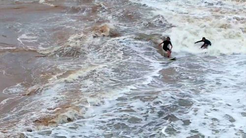 A group of Dee Why surfers have been hailed "heroes" after saving a man being swept out to sea during the city's wild weather.