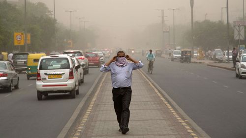 A man wraps a scarf around his nose as a dust storm envelops the city in New Delhi, India. (AP).