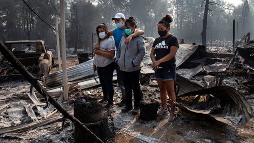 A family looks at the destruction of their home at Coleman Creek Estates mobile home park in Phoenix, Oregon.