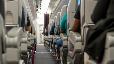 Interior of an airplane with passengers sitting on seats. 