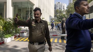 A police officer and a private security guard ask journalists to leave from the gate of a building housing BBC office in New Delhi, India, Tuesday, Feb. 14, 2023. 