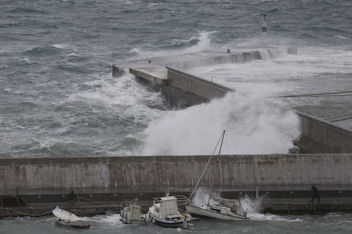 A man tries to secure a boat due to bad weather at the port of Rafina.
