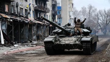 A Ukrainian tank drives down a street in the heavily damaged town of Siversk 