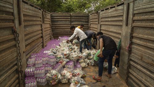 Cambodian volunteers help unload a supply truck at a resettlement camp, established to house thousands of people fleeing the Thailand-Cambodia clash,