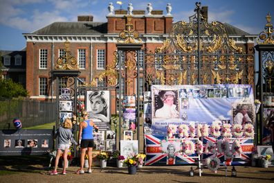 Two people stop to look at the messages and photographs outside Kensington Palace as fans of Princess Diana gather to show their support on August 31, 2022 in London, England.  