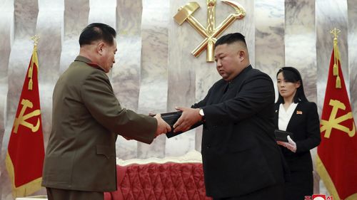 In this Sunday, July 26, 2020, photo released by the North Korean government, North Korean leader Kim Jong Un, center, hands over a Paektusan commemorative pistol to a senior military official during a ceremony in Pyongyang, North Korea. 