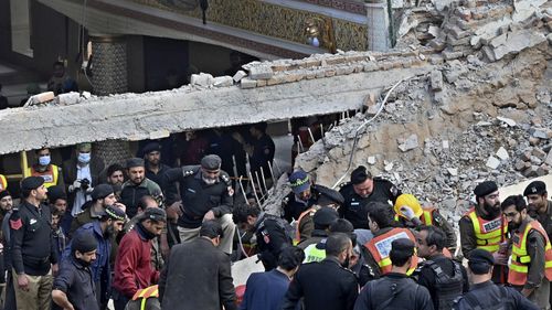 Security officials and rescue workers search bodies at the site of suicide bombing, in Peshawar.