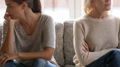 Daughter-in-law and mother-in-law sitting on a couch facing opposite ways