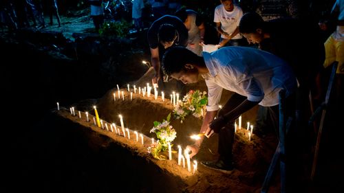 Relatives light candles after burial of three victims of the same family, who died at Easter Sunday bomb blast at St. Sebastian Church 