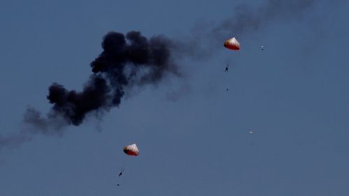Pilots from the Indonesian Jupiter aerobatics team were forced to eject and parachute to safety after the mid-air collision. (AAP)
