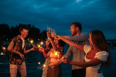 Friends drink together and celebrate with sprinklers on the catamaran deck
