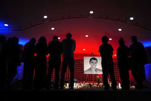Charlie Kirk için düzenlenen anma etkinliğinde insanlar fotoğrafını inceliyor.