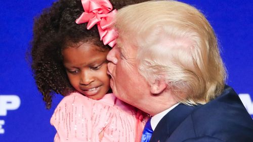 The child squirms as Trump plants a kiss on her. (AAP)
