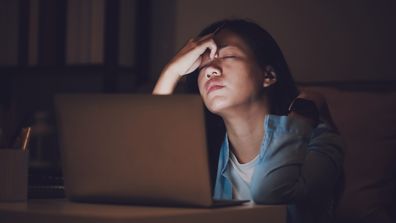 Overtired woman working late at night. Woman on computer at night. Woman working late at night. Tired woman.