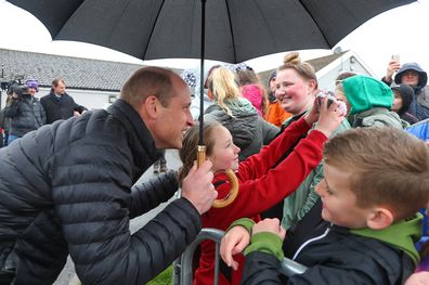 MERTHYR TYDFIL, WALES - APRIL 27: Britain's Prince William, Prince of Wales poses for a selfie photograph with a young wellwisher during a visit the Dowlais Rugby Club, in Dowlais, as part of a tour of Wales, on April 27, 2023 in Merthyr Tydfil, Wales. The Prince and Princes of Wales are visiting the country to celebrate the 60th anniversary of Central Beacons Mountain Rescue and to meet members of local communities. (Photo by Geoff Caddick - WPA Pool/Getty Images)