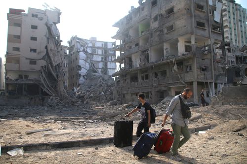 Palestinian citizens evacuate their homes damaged by Israeli airstrikes