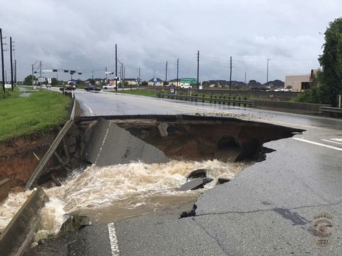 In this photo provided by the Rosenberg Police Department, water rushes from a large sinkhole on Highway FM 762 in Rosenberg, Texas, near Houston. (AP)