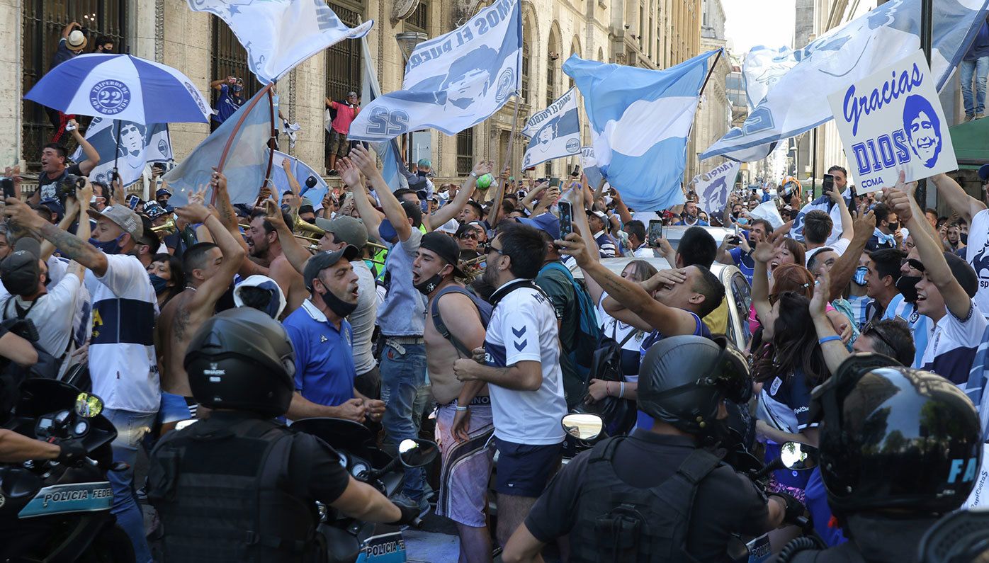 Fans sing and wave flags as the police tries to contain them during Diego Maradona&#x27;s funeral in Buenos Aires, Argentina.