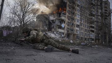 A Ukrainian police officer takes cover in front of a burning building that was hit in a Russian airstrike in Avdiivka, Ukraine, Friday, March 17, 2023. (AP Photo/Evgeniy Maloletka)