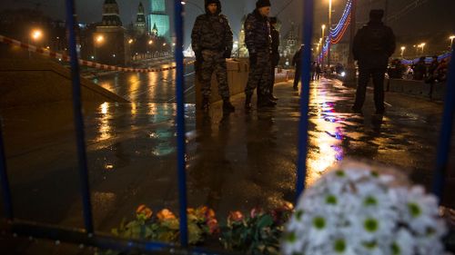 Flowers lie on the ground as Russian police officers stand near the place where Boris Nemtsov died. (AAP)