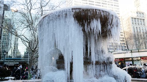 Pedestrians pass the water fountain at Bryant Park in New York on December 28, 2017. (AAP)