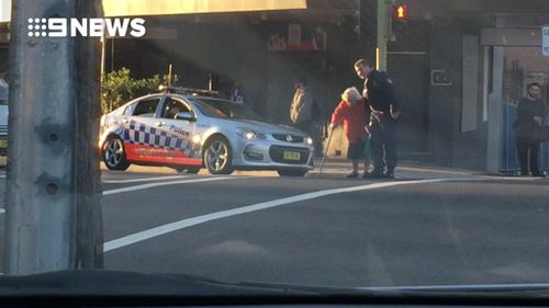 A witness told 9news.com.au not a single car honked as the officer helped the woman across the road. (9NEWS)