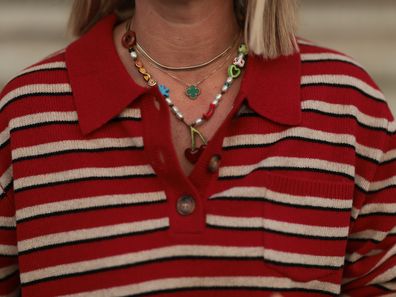 BERLIN, GERMANY - AUGUST 13: Karin Teigl seen wearing Baum & Pferdgarten red-and-white striped long-sleeve polo sweater, colorful playful beaded necklaces including a cherry pendant, Van Cleef & Arpels gold Alhambra necklace, on August 13, 2025 in Berlin, Germany. (Photo by Jeremy Moeller/Getty Images)