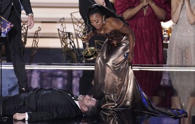 Quinta Brunson, right, winner of the Emmy for outstanding writing for a comedy series for "Abbott Elementary", checks on Jimmy Kimmel as he lays on stage at the 74th Primetime Emmy Awards