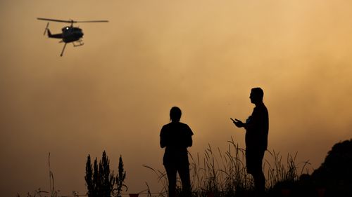 A water bombing helicopter is seen through a smoke haze in Forster, NSW mid-north coast, Thursday, November 7, 2019. 