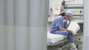 Sad nurse sitting on a hospital bed