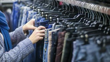 Woman looking at jeans on rack in shops