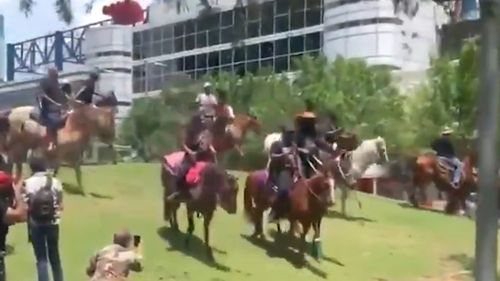 Horsemen and women ride down a bank in Houston, during a George Floyd march.