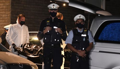 Employees of a funeral company carry a corpse to a hearse under the protection of police officers, Thursday, Sept. 3, 2020, in Solingen, Germany. 