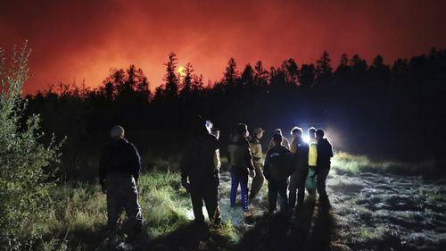 Firefighters and volunteers have a briefing as they work at the scene of forest fire at Gorny Ulus area west of Yakutsk, in Russia.
