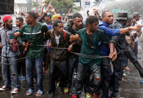 Papuan student activists are hit by a jet of a water from a water canon during clashes with Indonesian police in Jakarta, in 2016.