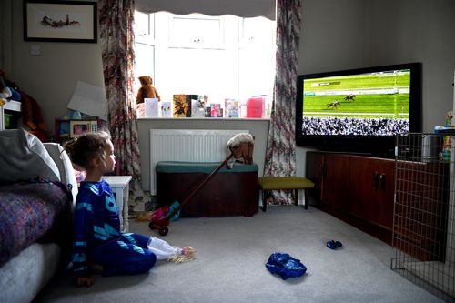 UK girl Lois Copley-Jones, aged 5, who is the photographer's daughter, watches the virtual Grand National 