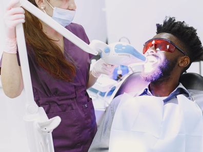 Stock photo of a man having his teeth whitened at the dentist.