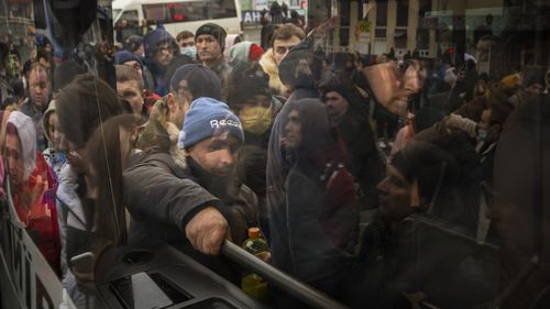 People try to get on a bus as they leave Kyiv, Ukraine.