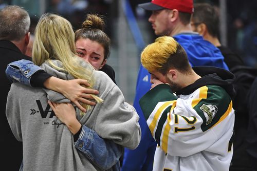 Mourners embrace each other during a moment of prayer at a vigil at the Elgar Petersen Arena.