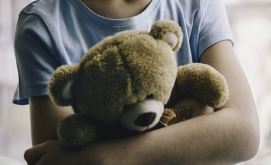 sad child holding teddy bear