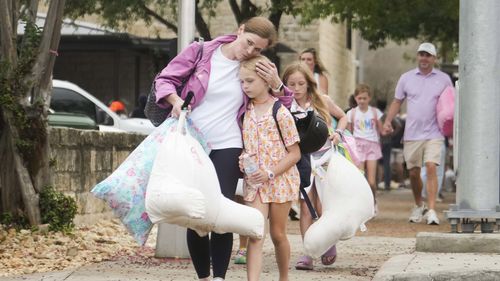 A woman and a child embrace after girls from Camp Waldemar, near the North fork of the Guadalupe River.