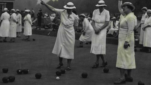 Women play lawn bowls.