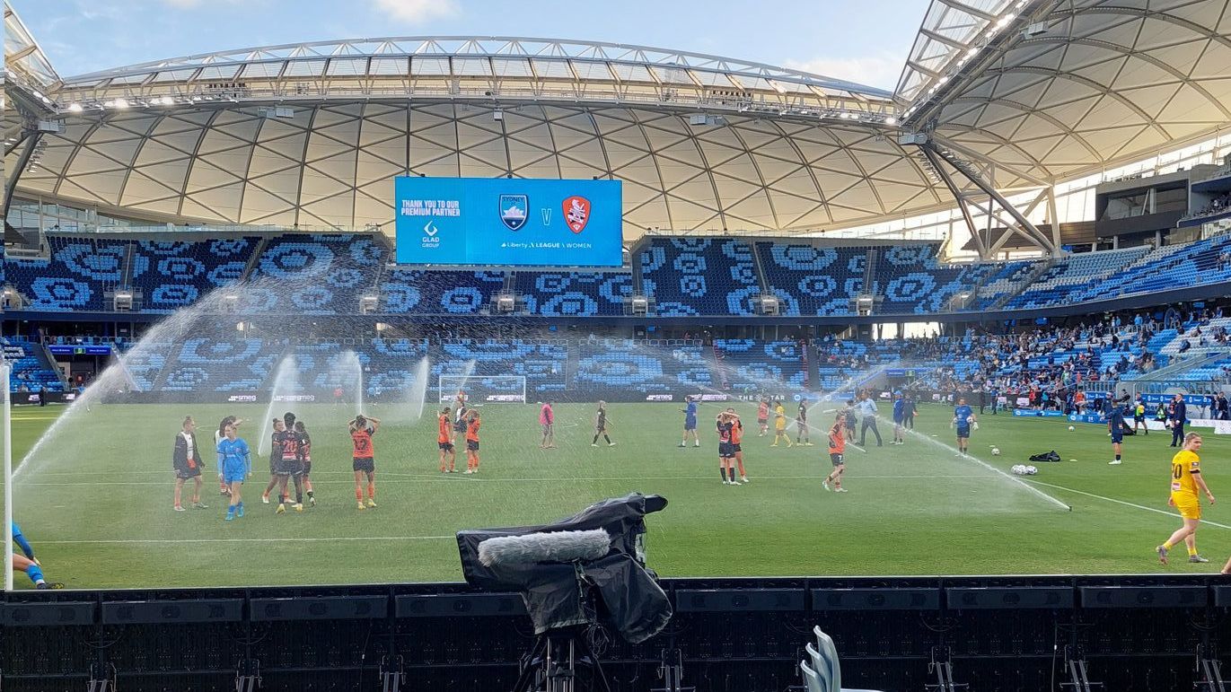 The sprinkler system goes off at Allianz Stadium with female players still on the pitch.