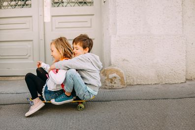 Photo of a two children riding the skateboard down the city streets