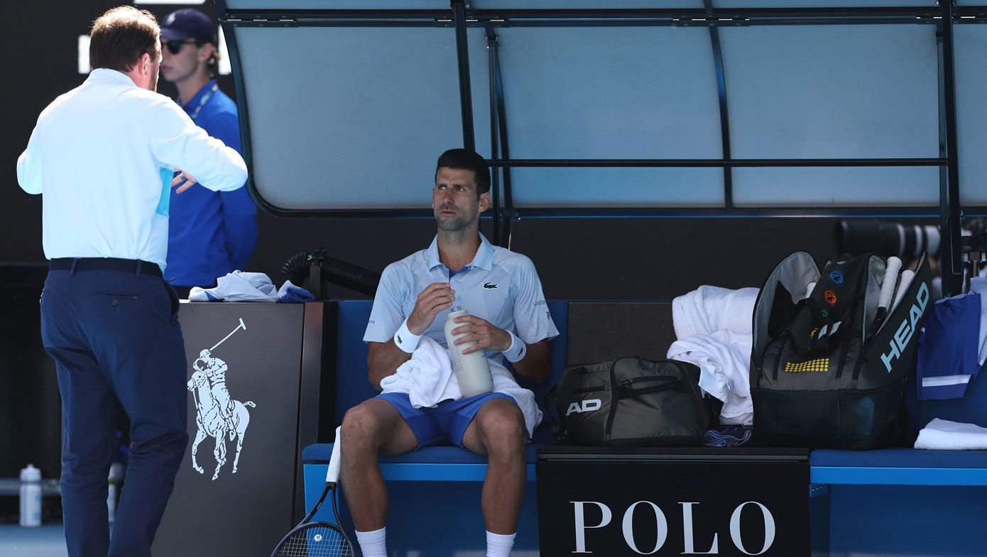 Novak Djokovic sits down while his semi-final against Jannik Sinner is paused so a spectator in the stands can receive medical treatment.