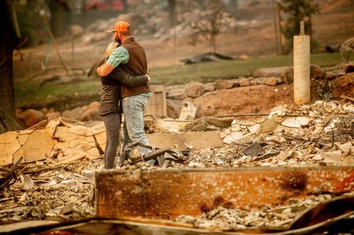 Chris and Nancy Brown embrace while searching through the remains of their home, leveled by the Camp Fire, in Paradise.