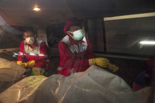 Rescue personnel accompany body bags to the hospital.